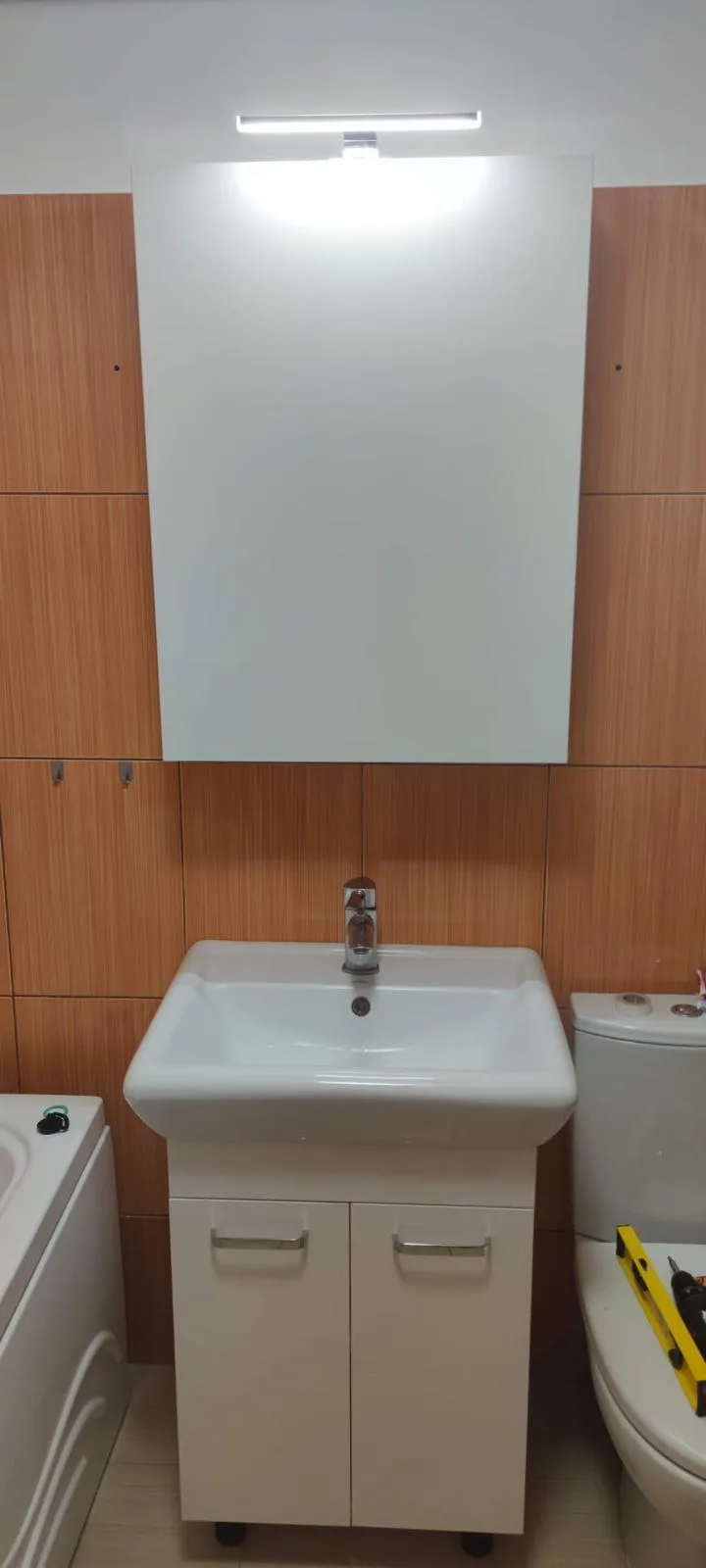 Lavoarul cu bază albă și dulapul-oglindă deschis, cu rafturi interioare